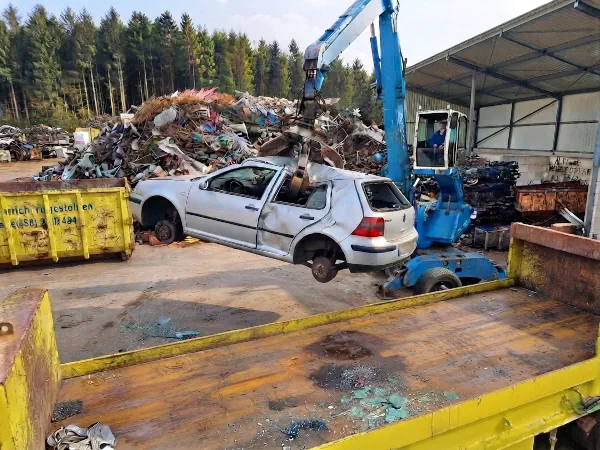 Autoverschrottung Castrop-Rauxel: Schrottauto wird auf einem Verwertungshof mit einem Greifer zur Schrottpresse bewegt