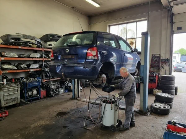 Autoverschrottung Herdecke: Mitarbeiter führt die fachgerechte Trockenlegung eines Schrottautos im Fahrzeugverwertungsbetrieb durch