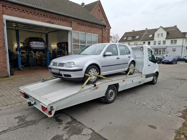 Autoverwertung Castrop-Rauxel: Schrottauto steht verladen und gesichert auf einem Autotransporter vor einer Kfz-Werkstatt