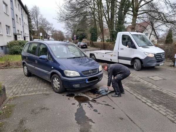 Schrottauto verliert unter dem Motor Öl und steht zur Abholung mit einem Autotransporter bereit