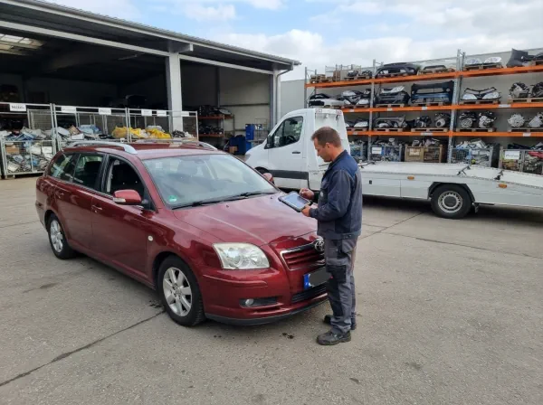 Mitarbeiter erfasst ein Schrottauto bei einem Fahrzeugverwerter digital