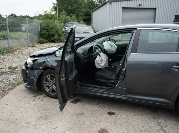 Beschädigtes Auto nach einem Unfall mit sichtbar ausgelösten Fahrer- und Beifahrerairbags